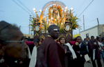 Peruvians carry a religious statue through the streets as both a black woman (observes in the foreground) and a black man (amongst those carrying the statue) are prominent in the photograph.