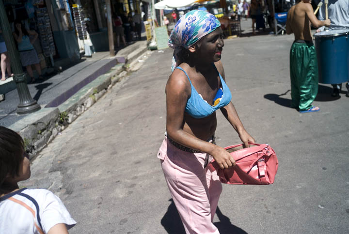 A 12-year old Argentine girl, with her face covered in black makeup and dressed as a would-be prostitute, walks a street carrying an open purse asking for money.