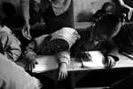 Teacher Nancy Vivian Obanda prepares to wake her baby class student, Stephen Maina, 2 years-9 months old, while Isaac Muriithi, 3-years old, does class work.