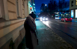 A rejected asylum seeker standing in the cold waits on an isolated street for a driver.