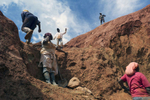 Four Afro-Colombian women stand idle on a mine hill as an Afro-Colombian man walks up.