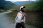 The photograph has a blurred effect showing an Afro-Bolivian man walking on a road with a rifle on his shoulder.
