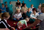Karen Hairston (foreground left) and Kym Hannah (foreground right), both physical therapists at Children's Therapy Services in Fayetteville, Arkansas, evaluate a child as Ukrainian caretakers observe. Over the course of three days, Hairston and Hannah put together an action plan with exercises and instructions for each special needs child at the orphanage. Future visits by volunteers will gauge the efficacy of both the caretakers' training and the children's treatment.