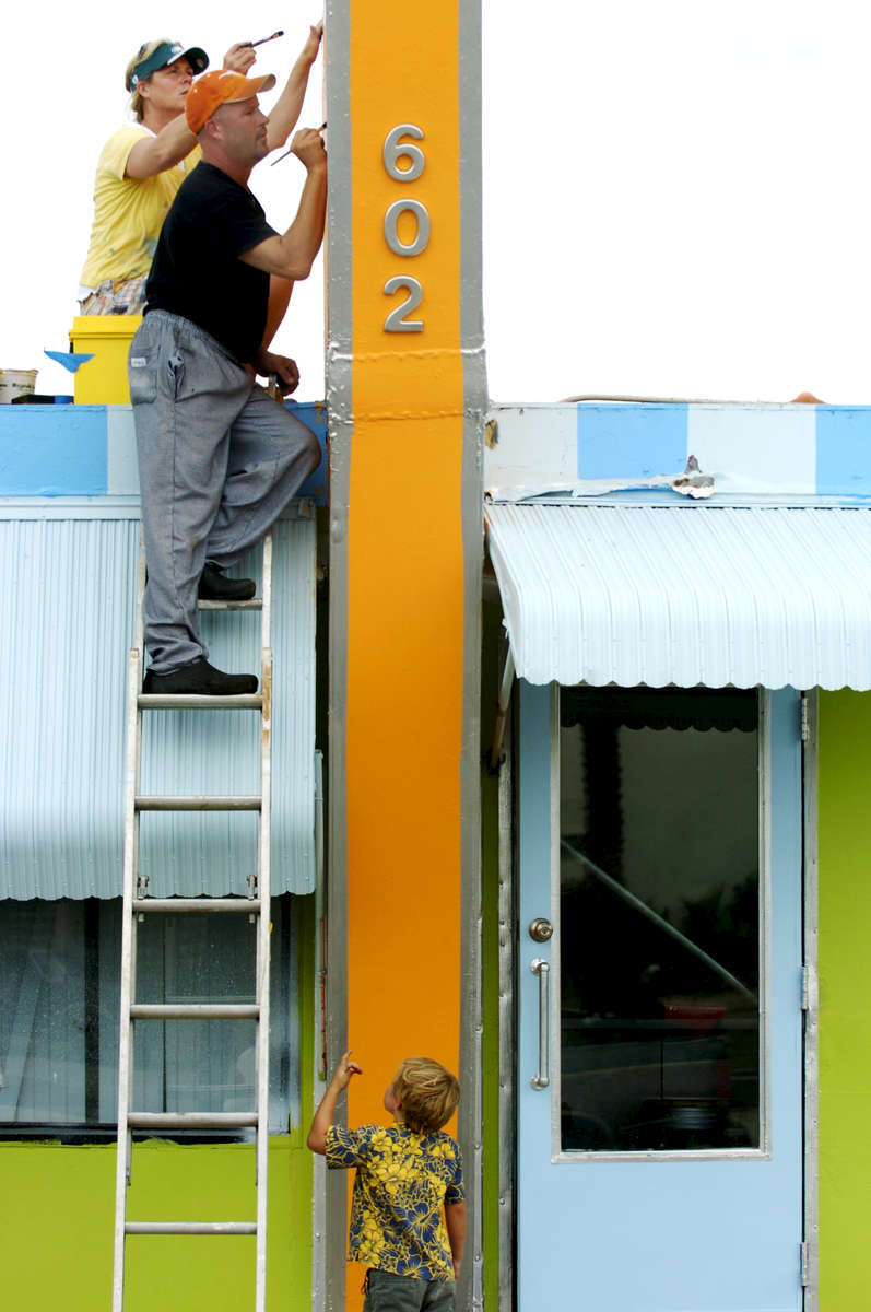 Dawn Surak and her brother Alan Laskowski paint letters on the sign of their Lucky Dog Diner in Venice, Florida, as Surak's son Ollie, 4, plays below them . 