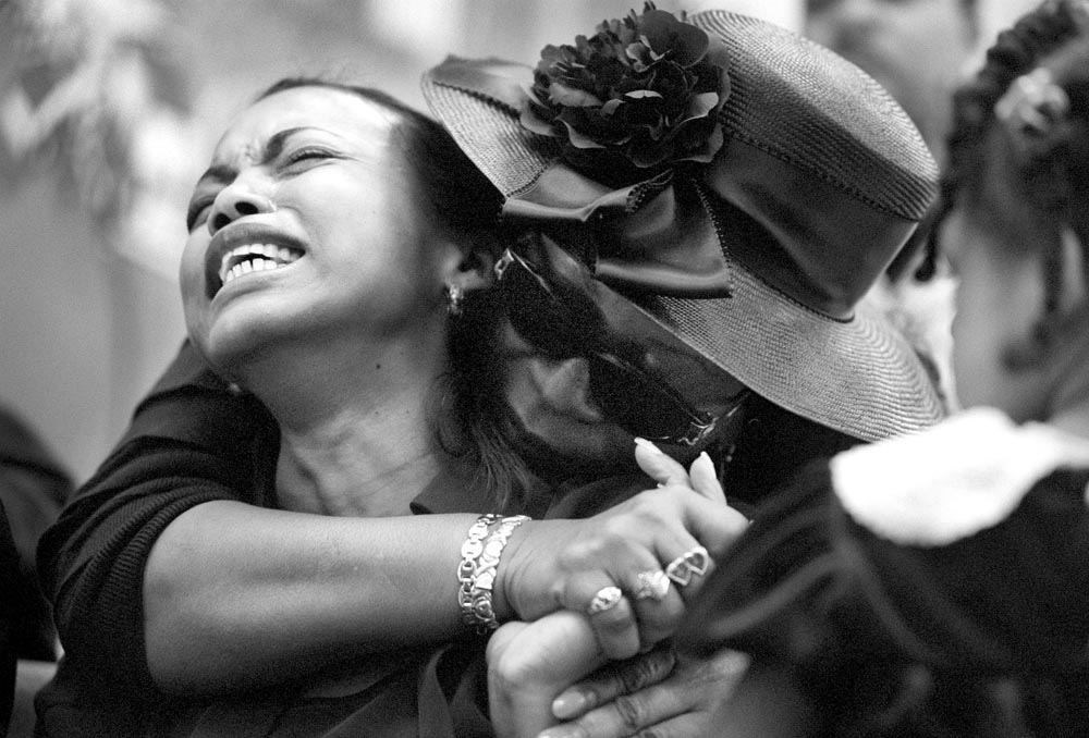 After remaining composed through a long memorial service, Sharon breaks down when a soloist sings a song in memory of her husband. Sharon's Aunt, Joyce, comforts her from behind. 