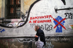 A woman walks by graffiti of the fist that came to symbolize civic protests against political corruption in 2013, seen in Bulgaria's capital Sofia, on October 4th, 2014. The fist has been crossed off by a second layer of graffiti, with an adjacent sign that reads, {quote}Communism, but not a Colony,{quote} in likely reference to what some political parties decry as Westernization of interests in the country. Bulgaria is still one of the poorest, most corrupt nations in the European Union, its post-1989 hopes wilted by political corruption, high crime rates and skyrocketing inflation. The ennui etches a permanent path across the average passerby's face, against a backdrop of rotting architecture, joblessness, and a vast population decline. 