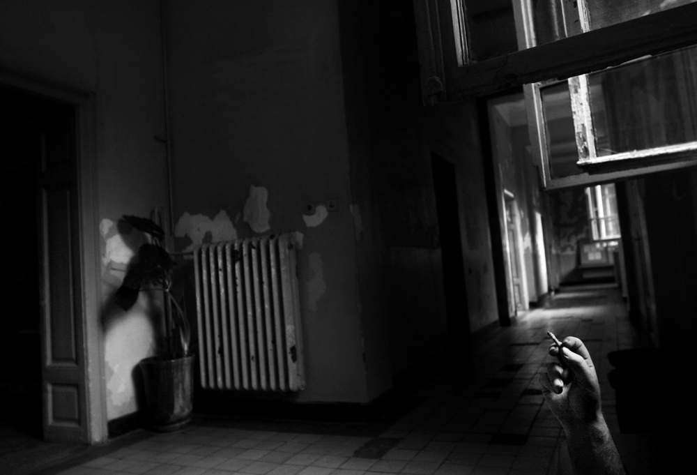 A patient smokes a cigarette in the empty hallway of the psychiatry ward of a county hospital in Bulgaria on August 20, 2007. Coffee and cigarette breaks are amongst the only methods of entertainment and distraction in the ward. 