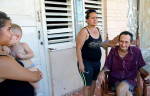 (L-R) Melani Conpagine, 13, holds her brother Mauro Peña, 1, next to the wife of a relative, Nancy Mena, 48, as she gives her father, Juaneto Mena, 82, a shave in the port city of Mariel, Cuba, a town whose tranquil appearance belies its important place in both the history and future of Cuban-American interaction. It is where Russians unloaded nuclear warheads in the 1962 Cuban missile crisis, and the gateway through which 125,000 Miami-bound emigres fled during the Mariel Boatlift of 1980. The town is now the site of construction of a deepwater container port and a free-trade zone, a critical ingredient for which will be the future of the U.S. embargo against Cuba, in place for more than 50 years but now under speculation of being lifted. 
