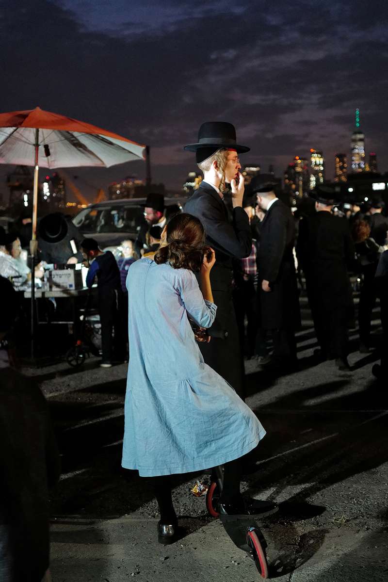 A young girl peeks into the all-men's section during Tashlich, an ancient annual Jewish ritual to cast off one's sins into the water, here performed over the Williamsburg section of the East River in Brooklyn, New York on September 24, 2020. Women and men are separated by religious tradition during Orthodox Jewish holidays and prayer, but this separation can extend to the social spheres of the community as well. In public life — in politics, for example — female candidates are expected to adhere to entirely different standards than their male counterparts, such as never showing their faces in community newspaper ads, based on a tradition that directs men to shield their eyes from potentially improper images of women. (Photo by: Yana Paskova for The New York Times/the National Geographic Society)