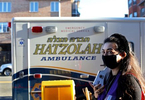 EMT trainee Adina Sash, 34, carries an Ezras Nashim donations piggy bank around Borough Park in Brooklyn, right past the competing all-male EMTs' Hatzolah ambulance on December 06, 2020. Ezrash Nashim is the first all-female EMT corps aimed at servicing Orthodox Jewish communities of women. On the importance of Ezras Nashim, Sash says, “When you have a community that filters education and access to information, especially about a woman’s agency over her body, then it becomes even more important to equip those very women with the choice of where to turn in an emergency. Especially if the emergency is relevant to her reproductive system, having to confide in males in the community is tricky. Whereas women can help other women navigate those issues better.”In addition to volunteering as a nurse for Ezras Nashim, in 2019 Sash ran for City Council in Brooklyn's 45th district as an Orthodox Jewish woman -- in a community that expects women to adhere to entirely different standards than male candidates, such as never showing their face in community newspaper ads, based on a religious tradition that directs men to shield their eyes from potentially improper images of women -- and says she considers herself a feminist. {quote}There needs to be more acceptance for women getting education in the Orthodox community, and the community is split on this. There is a 'If it’s not broken, don’t fix it' mentality because [all-male competing EMT organization] Hatzolah already exists, but there are others who understand inclusion of women leads to better care overall.{quote} On her motivations to run for office, to which she says she faced a lot of opposition from the community, she says: {quote}Making girls in the community aware that in addition to starting a family, there is importance to being part of the political process, challenges the narrative that it’s a mans job to run for office.{quote}(Photo by: Yana Paskova for The New York Times/the National Geographic Society)