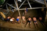 Indian men work out before practicing traditional Kushti wrestling while another prepares the soil for the sport on Monday, June 01, 2009 in New Delhi, India. 