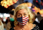 A masked woman walks through crowds gathering for the 95th Annual Feast of San Gennaro in the neighborhood of Little Italy in Manhattan, NY, on September 24, 2021, a festival that's gathered for the first time since 2019 after last year's festivities were canceled due to the coronavirus pandemic. 