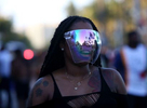 Ebony Chambers, 30, wears a face shields bought from a vintage shop in Atlanta while walking by the bars and restaurants on South Beach’s Ocean Drive, during Spring Break in Miami, Florida on March 26, 2021, before Miami police enforce an 8 PM curfew. Mask-less spring breakers flooding Miami’s beaches caused concerns of a new coronavirus surge.