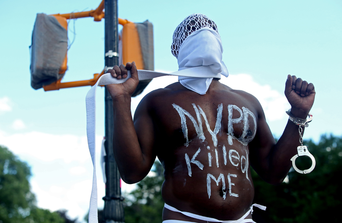A masked protester stands amidst a gathering of hundreds at Grand Army Plaza in Brooklyn, New York, on June 07, 2020. Peaceful demonstrations, which elicited teargassing, rubber bullets and mass arrests by police, spread throughout the country and the world in response to the death of George Floyd, an African-American man who Minneapolis police killed via extensive neck and back compression during an arrest at the end of May. Photo by: Yana Paskova © 2020