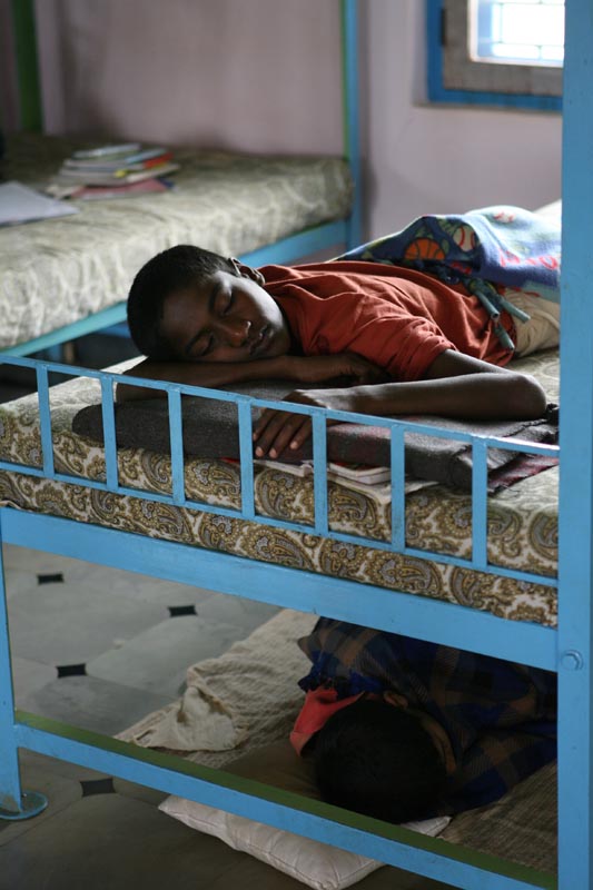 Arunkumar takes a Saturday afternoon nap on his bunk bed, while another child sleeps on the floor due to the lack of beds.