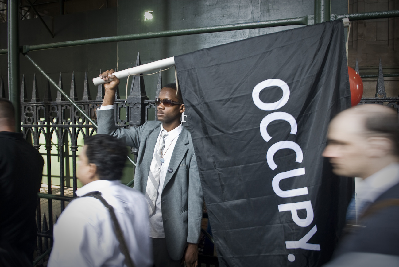 A man holds an Occupy banner aloft on lower Broadway near Wall Street on the morning of September 17th, the first year anniversaryof the Occupy Wall Street movement.