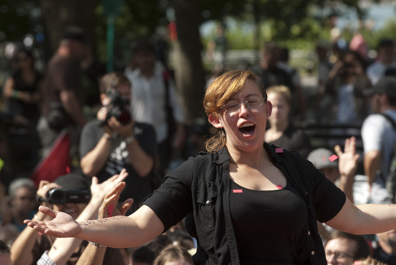 Pink confetti flutters down in front of a young woman as she addresses the Action Spokescouncil held by OWS supporters in Battery Park on September 17th 2012 the first anniversary of the Occupy Wall Street movement.