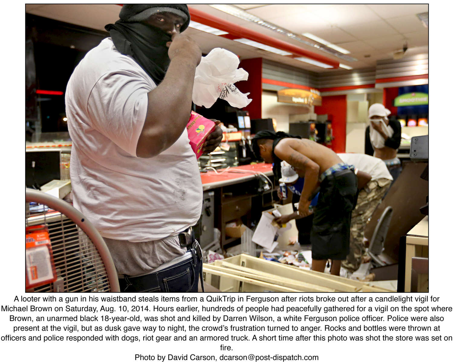 A looter with a gun in his waistband steals items from a QuikTrip in Ferguson after riots broke out after a candlelight vigil for Michael Brown on Saturday, Aug. 10, 2014. Hours earlier, hundreds of people had peacefully gathered for a vigil on the spot where Brown, an unarmed black 18-year-old, was shot and killed by Darren Wilson, a white Ferguson police officer. Police were also present at the vigil, but as dusk gave way to night, the crowd’s frustration turned to anger. Rocks and bottles were thrown at officers and police responded with dogs, riot gear and an armored truck. A short time after this photo was shot the store was set on fire.Photo by David Carson, dcarson@post-dispatch.com
