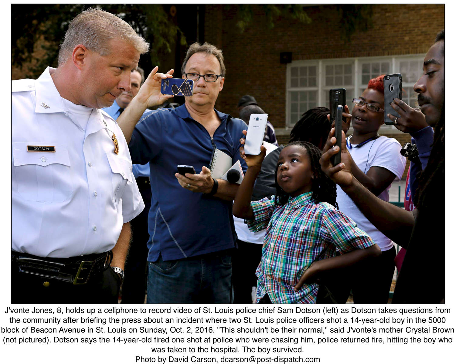 J'vonte Jones, 8, holds up a cellphone to record video of St. Louis police chief Sam Dotson (left) as Dotson takes questions from the community after briefing the press about an incident where two St. Louis police officers shot a 14-year-old boy in the 5000 block of Beacon Avenue in St. Louis on Sunday, Oct. 2, 2016. {quote}This shouldn't be their normal,{quote} said J'vonte's mother Crystal Brown (not pictured). Dotson says the 14-year-old fired one shot at police who were chasing him, police returned fire, hitting the boy who was taken to the hospital. The boy survived.Photo by David Carson, dcarson@post-dispatch.com