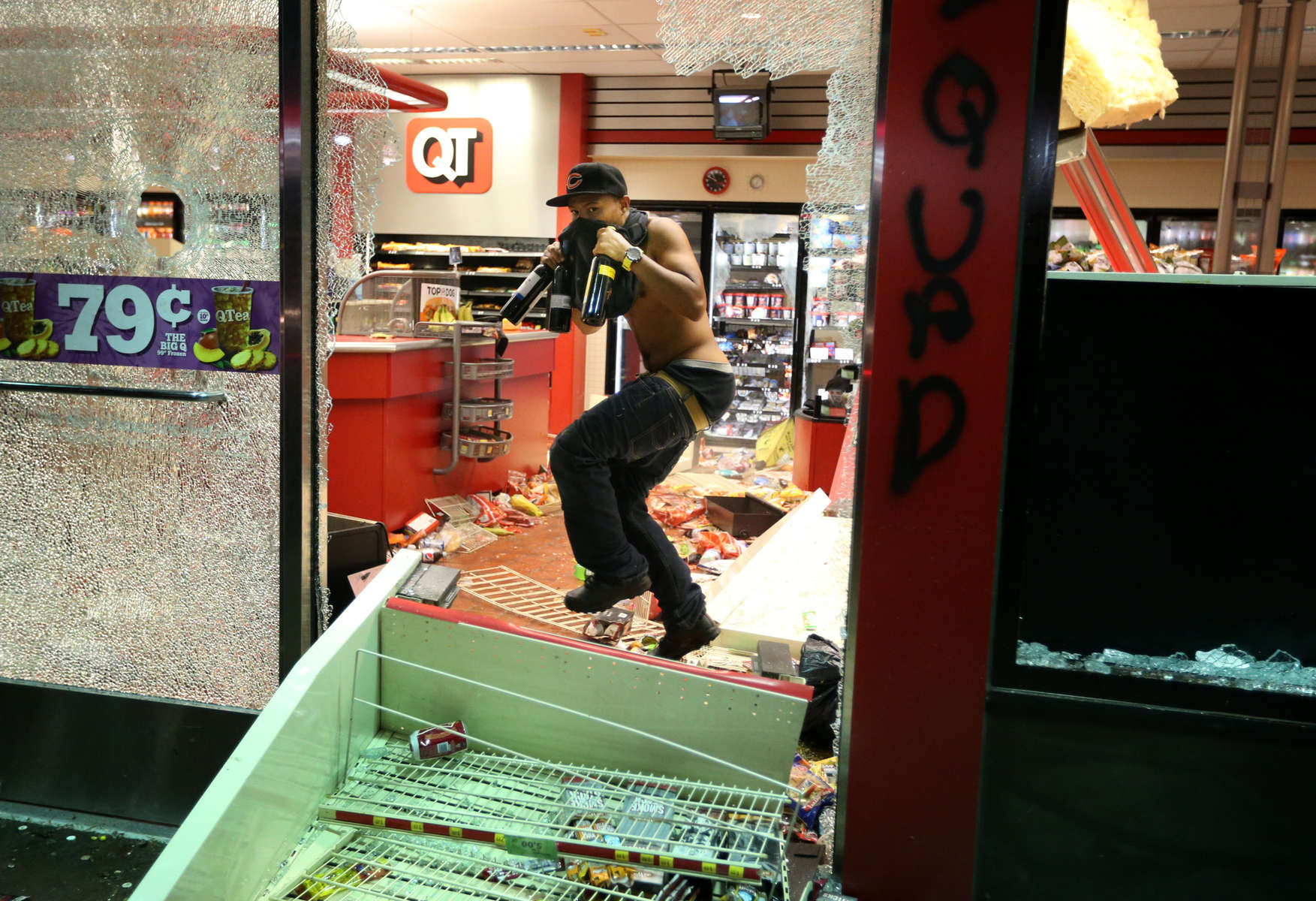 A looter takes items from inside the QuikTrip in 9400 block of W. Florissant Avenue in Ferguson, Mo. on Sunday, Aug. 10, 2014. Rioters set fire to the store about an hour later.
