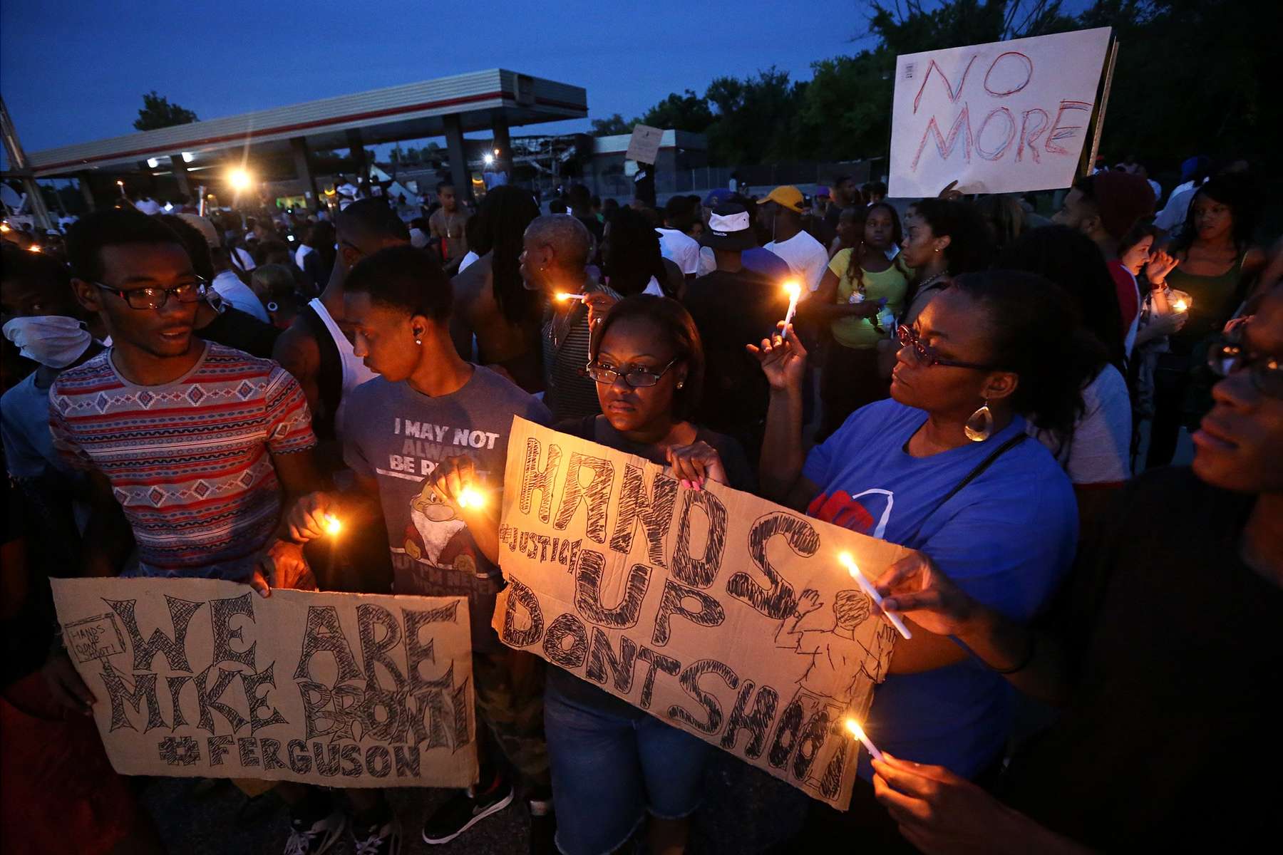 Keith Lovett (left), Melik Smith, Victoria Smith, Linda Smith and Antonio McDonald(right) hold candles during a gathering of people at the QuikTrip in Ferguson Thursday, Aug. 14, 2014.  Thursday marked the first peaceful night protests since Michael Brown was shot and killed by a police officer.