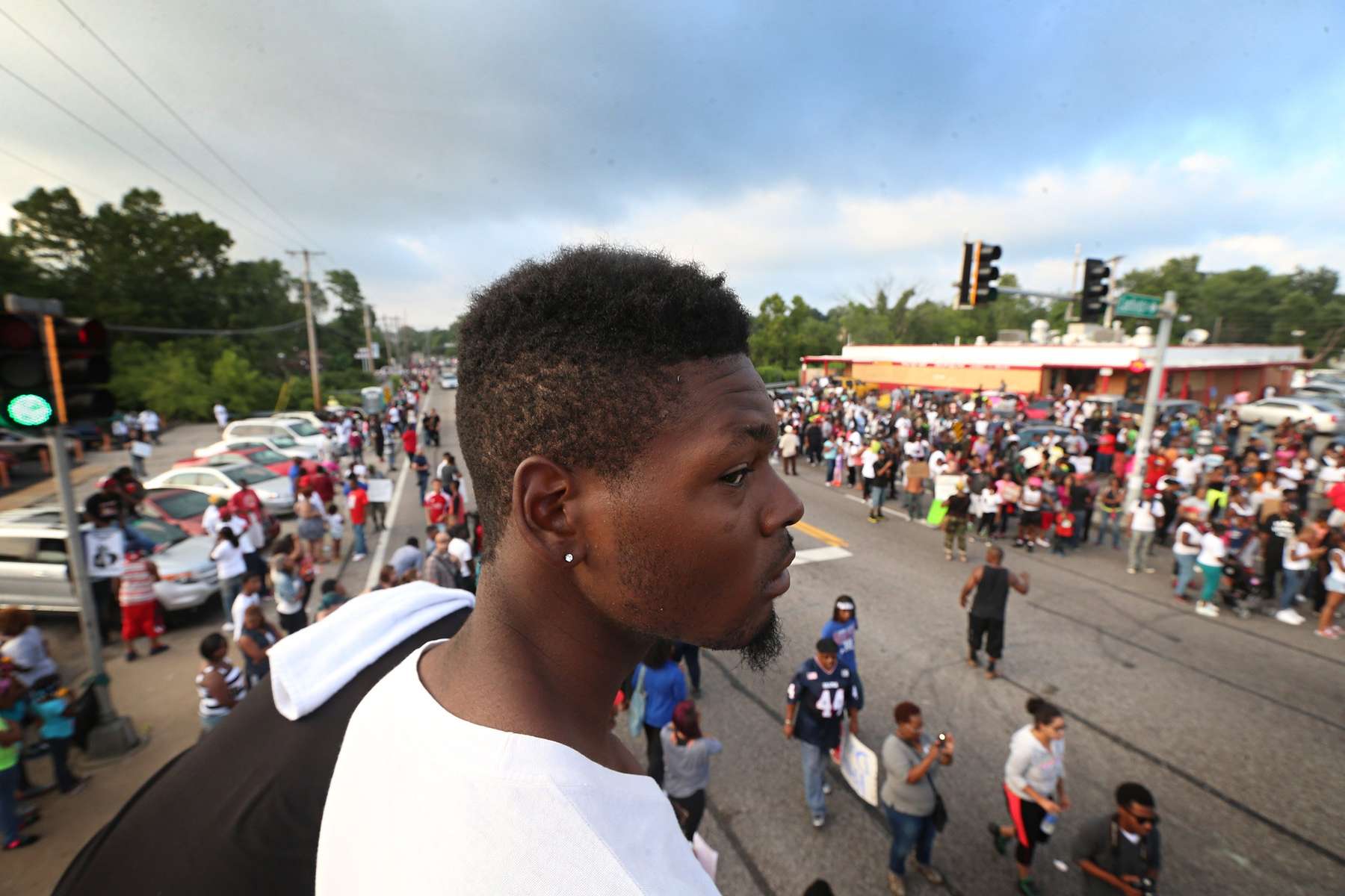 Jamel Easley, from the Walnut Park neighborhood in St. Louis city, takes in the scene from on top of a van parked at the corner of Canfield Drive and W Florissant Avenue on Sunday, Aug. 17, 2014.Photo By David Carson, dcarson@post-disptch.com