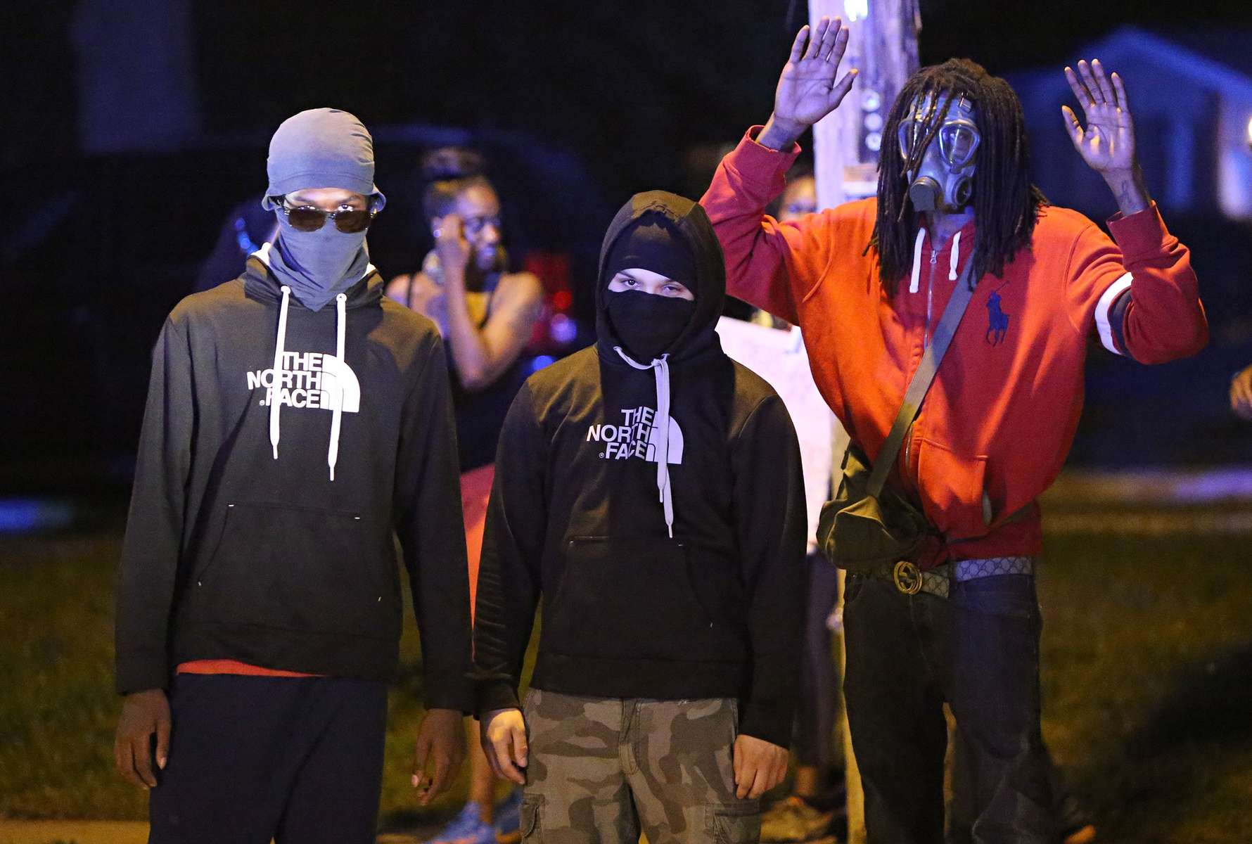 A group of protesters looks at a line of police gathered near the QuikTrip on Florissant Road in Ferguson, Mo. on Monday, Aug. 18, 2014.