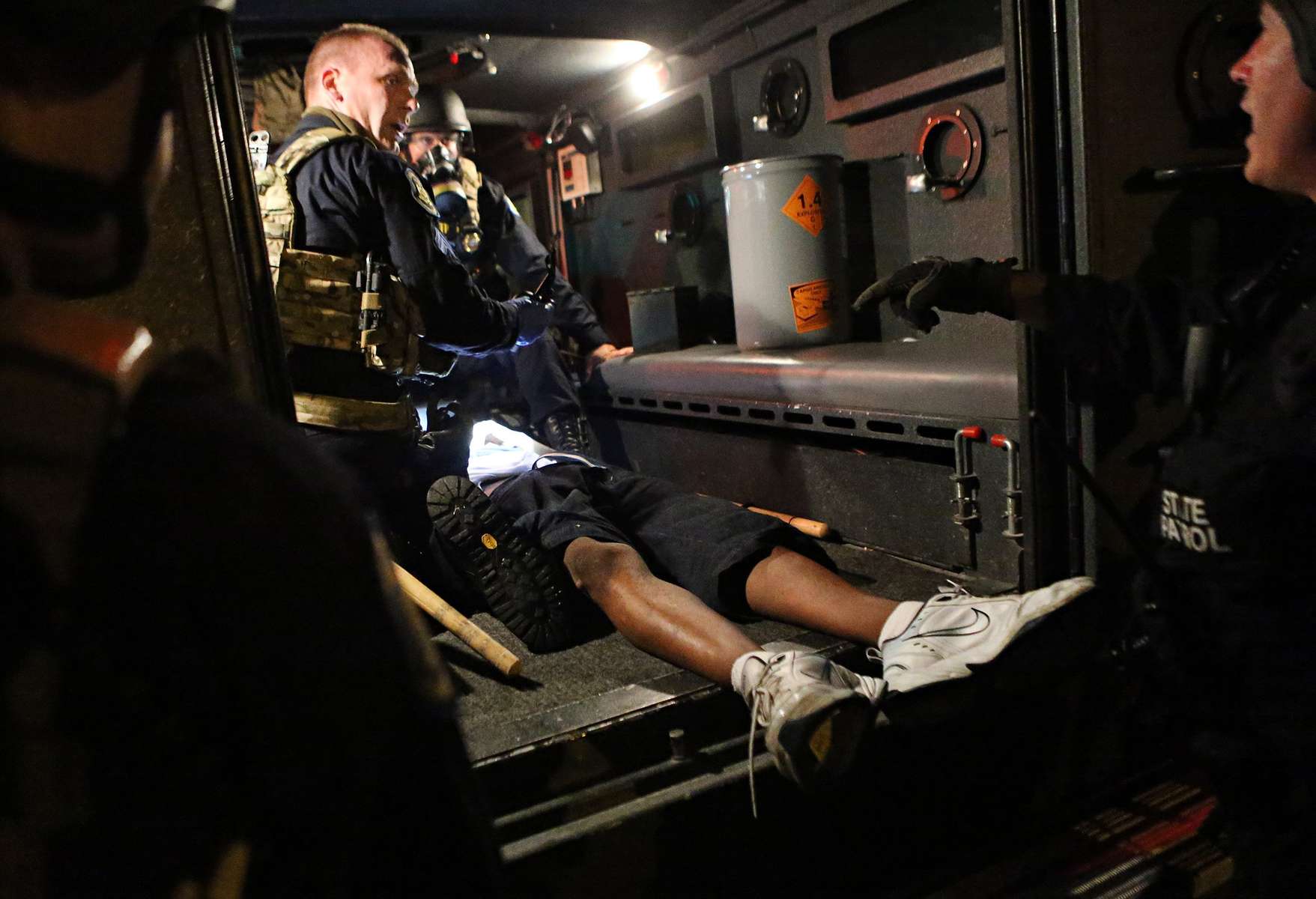 Members of the Missouri Highway Patrol tactical team treat an injured man found in a ditch during demonstrations along W. Florissant Road near the QuikTrip in Ferguson, Mo. on Tuesday, Aug. 19, 2014.