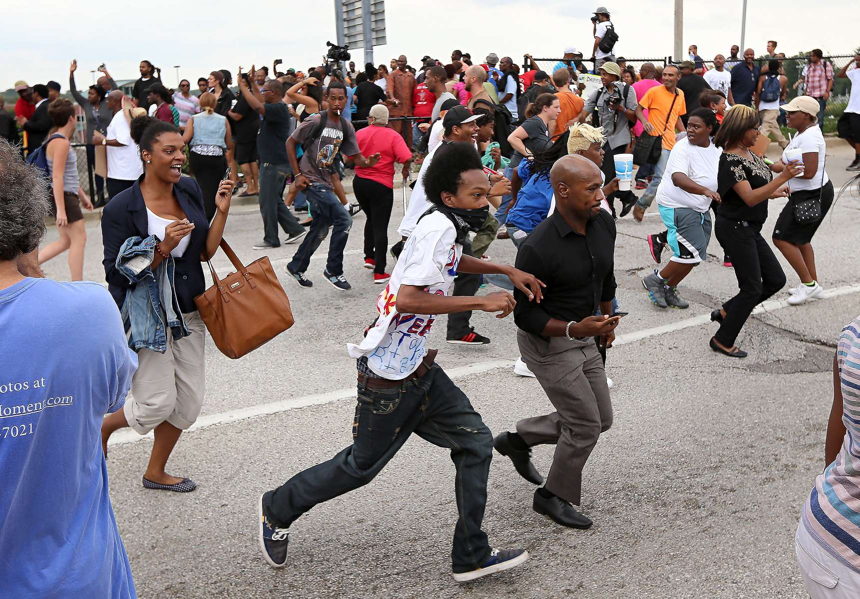Members of the crowd scatter as police rush into a sea of people in an attempt to make an arrest during a demonstration on Hanley Road at Interstate 70 in St. Louis County on Wednesday, Sept. 10, 2014.  Protesters had announced their intention to shutdown traffic on Interstate 70 to protest the fatal shooting of Michael Brown by a Ferguson police officer but police block protesters access to the highway.