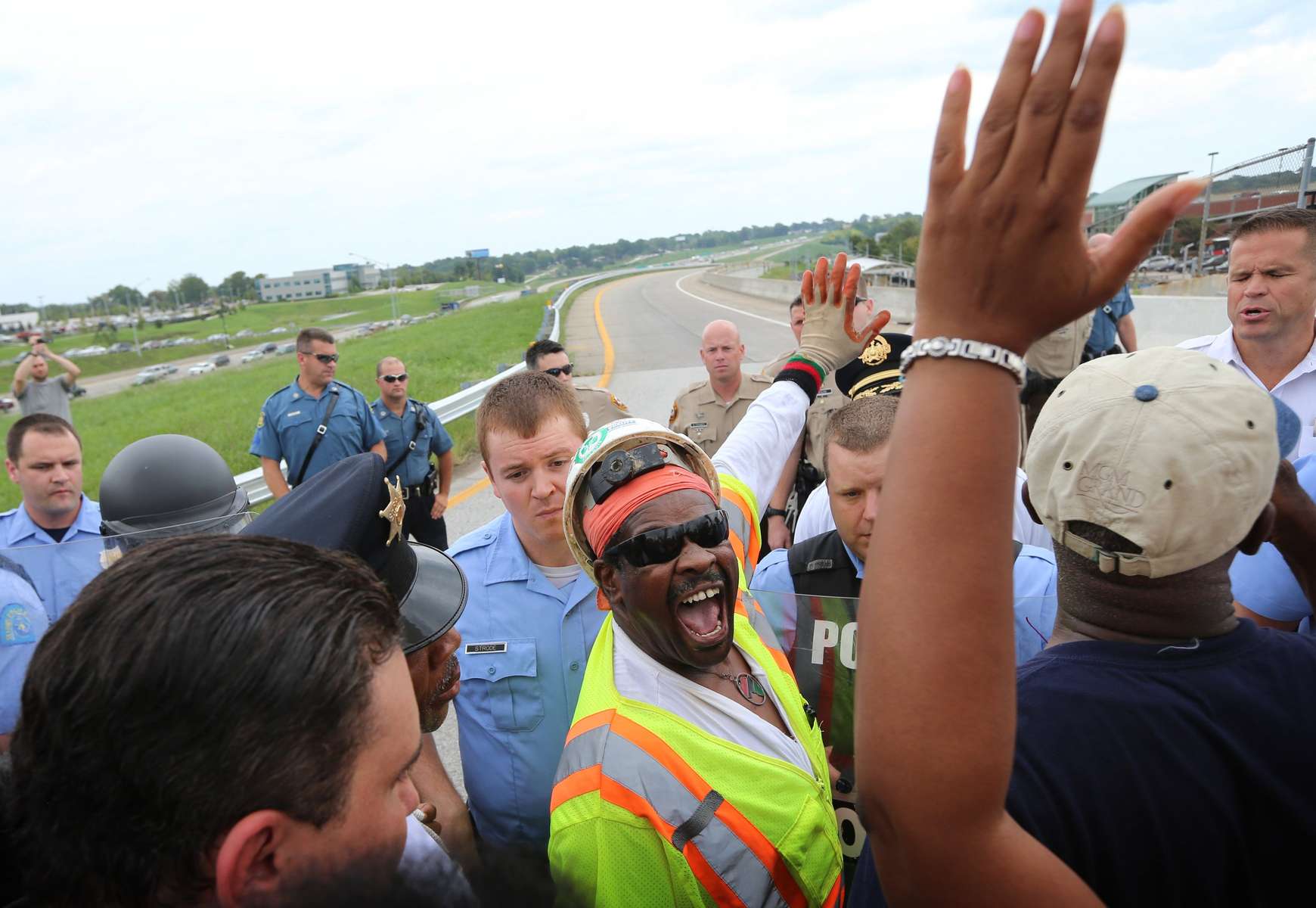 Cleo Willis (center) yells to fellow demonstrators squaring office with police who were blocking the on ramp to Interstate 70 East at Hanley Road during a demonstration in St. Louis County on Wednesday, Sept. 10, 2014.  Protesters had announced their intention to shutdown traffic on Interstate 70 to protest the fatal shooting of Michael Brown by a Ferguson police officer but police blocked protesters access to the highway.