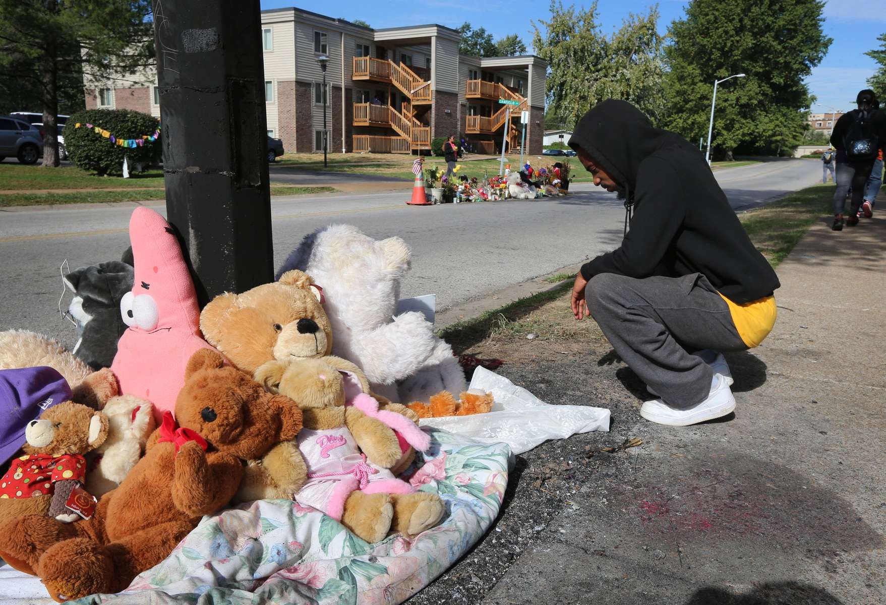 Tim Sneed kneels at Michael Brown's memorial that had burned earlier in the day as a new pile of stuffed animals and items began to appear at the spot on Canfield Drive on Tuesday, Sept. 23.  The fire started somewhere between 6:30 and 7 A.M