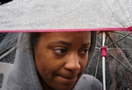 Lakeyra Stephens, 20, takes shelter from the rain under her umbrella after she marched with protesters around downtown Clayton during the first Ferguson October protests on Friday, Oct. 10, 2014.  About 400 people too part in the march and protest aimed at getting justice for Michael Brown and to get St. Louis County prosecuting attorney's Bob McCulloch to step aside and bring in a special prosecutor.  Stephens, a Webster University student from Texas, says she showed put show solidarity with the protesters.  She went on to say that she was surprised by the level of segregation she sees in St. Louis compared to Texas.