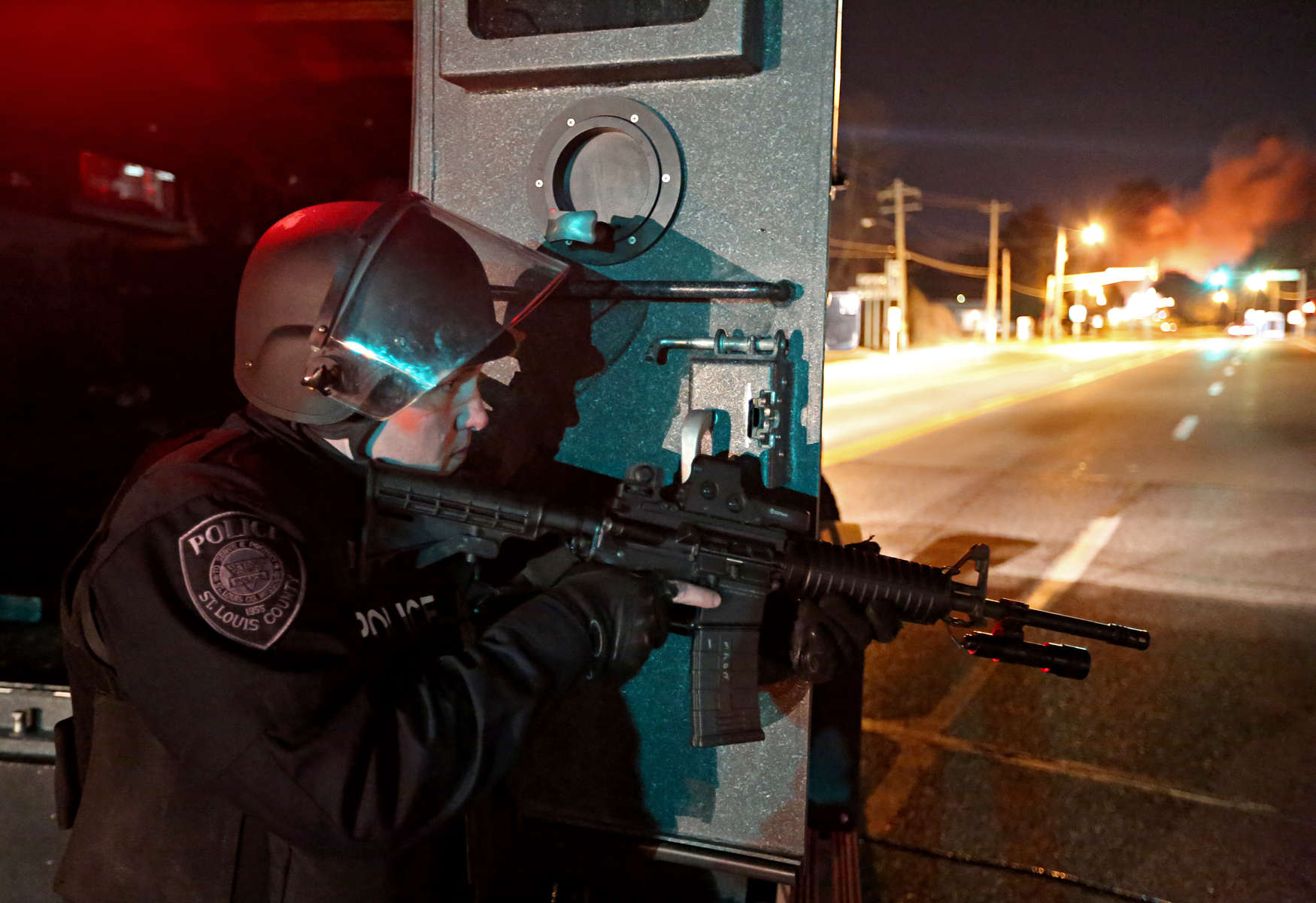 A police officer keeps an eye out for movement along West Florissant Avenue in Ferguson on Tuesday, Nov. 25, 2014.   Smoke from a burning building can be seen rising to the right.Photo By David Carson, dcarson@post-dispatch.com