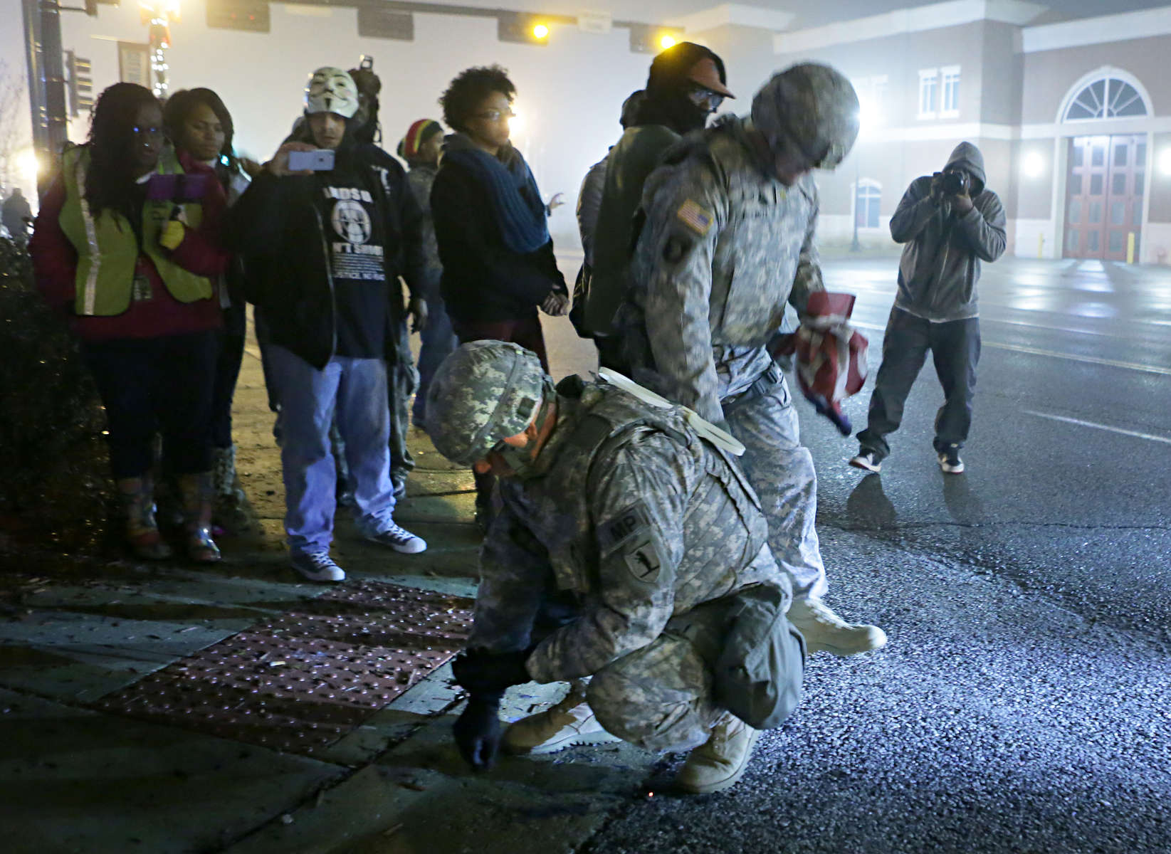 Missouri National Guard soldiers Sgt. First Class Eric Allison (left) and Major Lance Dell collect pieces of an American flag protesters burned and tossed to the ground outside the Ferguson police department Thursday, Dec. 4. 2014.  {quote}They're treating it as trash, it's not trash to us.  We're not going to let them throw it on the ground and leave it there{quote} said Dell. Photo By David Carson, dcarson@post-dispatch.com