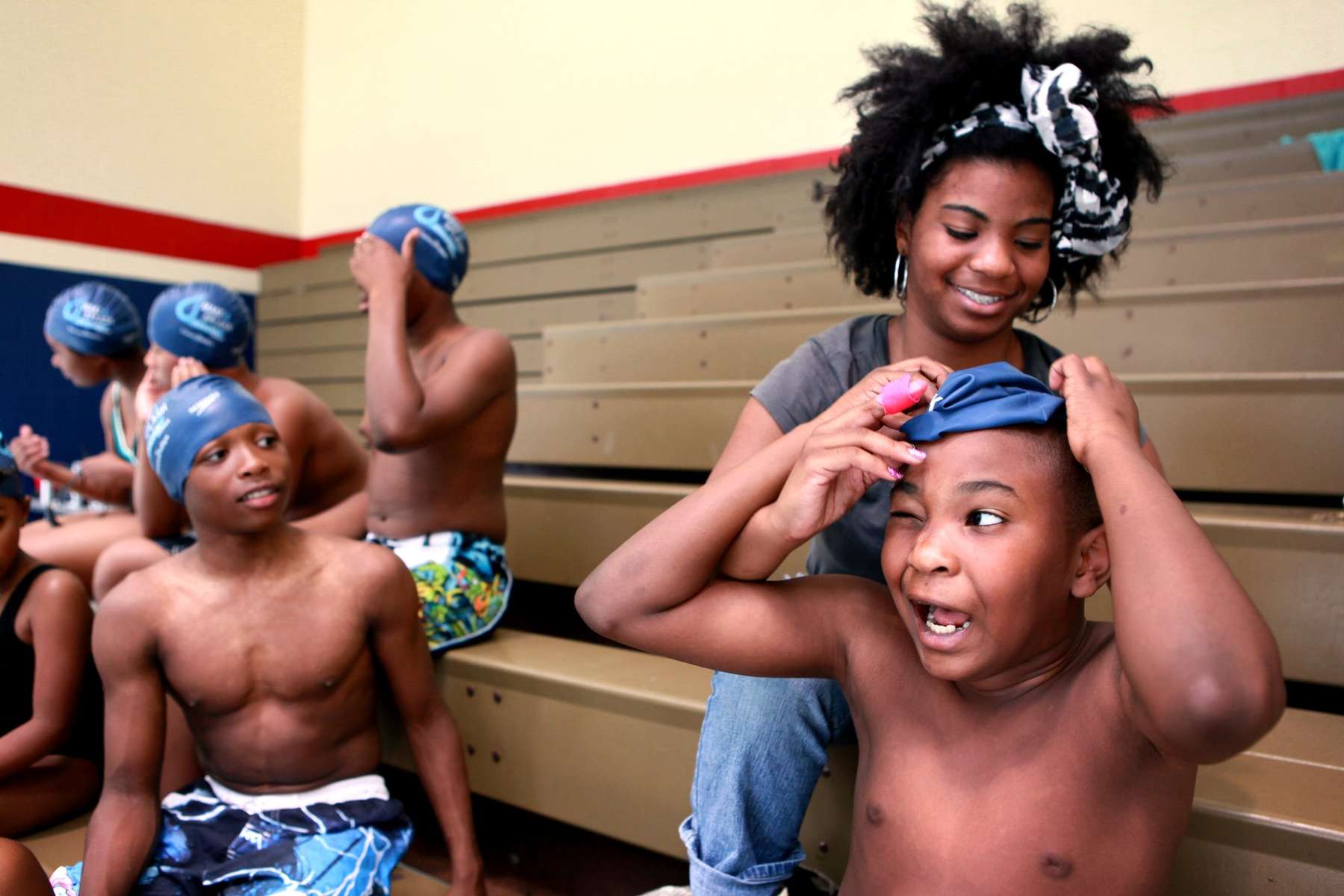 Mekkah Richards, 15, helps her brother Abel Richards, 9, put on his swim cap before the start of event featuring Olympic gold medalist swimmer Cullen Jones at the Mathews Dickey Boys and Girls Club in St. Louis. The event, Make A Splash, put on by the USA Swimming Foundation, is designed to raise awareness about the importance of learning to swim.  The program has helped provide more than 845,000 kids with swimming lessons.