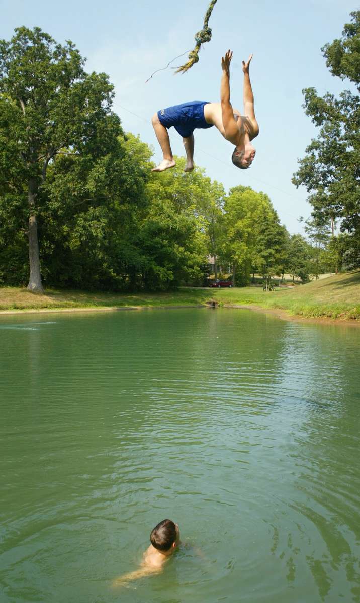 Monday August 5, 2002--Jake Whitehead, 16, of Edwardsville, launches himself off a rope swing into a pond as his friend Shaun Fink, 16, of Glen Carbon watches.  {quote}We're just hanging out, cooling off and having fun{quote} said Fink of their mid-afternoon dip in a swimming hole off of  Oaklawn Road in Glen Carbon on Monday.  Tempature will cool off into the upper 80's for Tuesday but return to the mid-90's later in the week.Photo By David Carson/PD