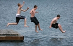 Friends Patrick Schertzer, left, Brett Ware, center, and Curtis Vitale take flying leaps into a man made lake at the New Town development in St. Charles County. Tempatures are expected to remain in the upper 80's and lower 90's for the through the weekend.