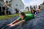 Grace Wickham (front), Rachel Hutson (center), Matt Wickham, and Reilly Newton get some help from Noah Cochran (left) as he hoses down the plastic sheeting while they launch themselves down a homemade Slip 'n Slide during a party at the Wickham's home in Weldon Spring on Monday May 28, 2012.  The Wickhams made the slide from a 100 foot roll of plastic sheeting, some sprinklers to wet the slide and dish soap to make it slippery. Photo By David Carson, dcarson@post-dispatch.com