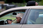 A man with a drawn gun watches police in his side rear view mirror as he drives slowly away from a line of advancing police trying to clear protesters off of Page Boulevard near the intersection of Walton Avenue on Wednesday, Aug. 19, 2015.St. Louis Post-Dispatch Photo