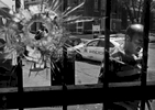 Renee Swink (left) is framed in a bullet hole punched through the front window of Yeatman Market in the 4400 block of Athlone Avenue on Monday, Aug. 3, 2015. The bullet hole is from a shooting that injured three people at about 11:30 a.m. One man suffered a gun shot wound to the leg, another man was hit in his ankle and arm and a third victim sustained a graze wound to his arm. All three victims are expected to survive. The shots were fired from a car at a man who was walking in front of the market. {quote}It's shocking{quote} said Swink whose daughter lives in an apartment above the store. Stray bullets also shattered the store's front glass doors, damaged some wood work and a soda machine. Also pictured is Mustafa Hamed (right) who was helping sweep up the broken glass.Photo By David Carson, dcarson@post-dispatch.com