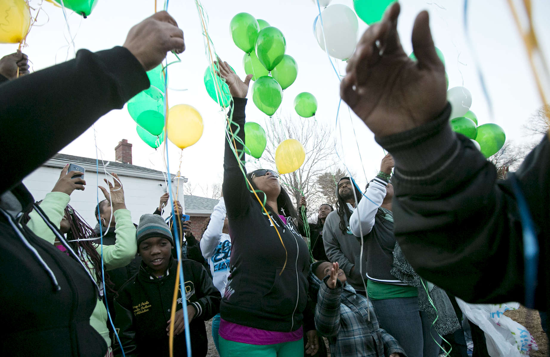 Shenelle Burgess (center) releases balloons with her family and friends at the grave of her son Pierre Childs at New Bethlehem Cemetery on Wednesday, March 5, 2014.  Police believe that Childs,16, was the unintended victim of a shooting on May, 7, 2013.  The family of Childs has been helped through the grieving and police investigation process by a minister assigned to the family by the police department.  The family gathered to release balloons to mark what would have been Childs' 17th birthday.  To date no one has been charged with Childs' murder.Photo By David Carson, dcarson@post-dispatch.com