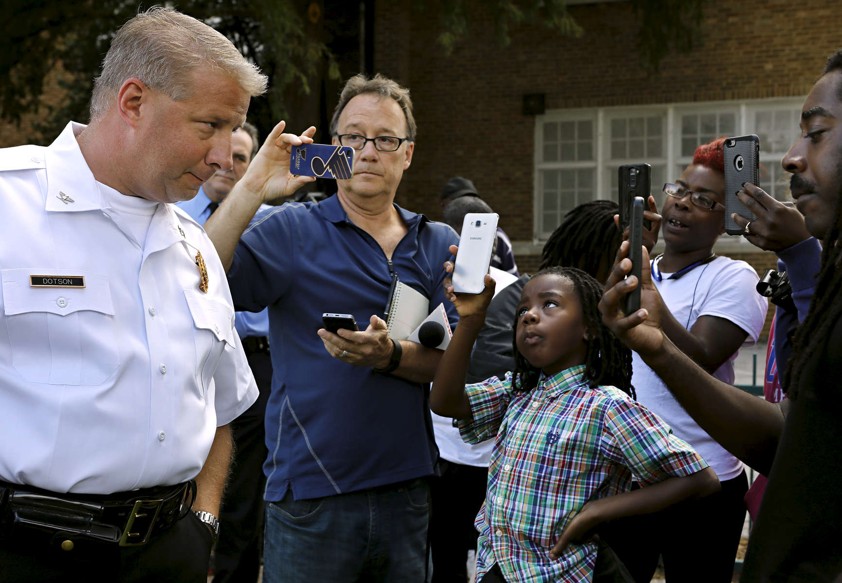 J'volte Jones, 8, holds up a cellphone to record video of St. Louis police chief Sam Dotson (left) as Dotson takes questions from the community after briefing the press about an incident where two St. Louis police officers shoot a 14 year-old boy in the 5000 block of Beacon Avenue in St. Louis on Sunday, Oct. 2, 2016. {quote}This shouldn't be their normal{quote} said J'vonte's mother Crystal Brown (not pictured). Dotson says the 14 year-old fired one shot at police who were chasing him, the police returned fire an unknown number of times hitting the boy.Photo by David Carson, dcarson@post-dispatch.com