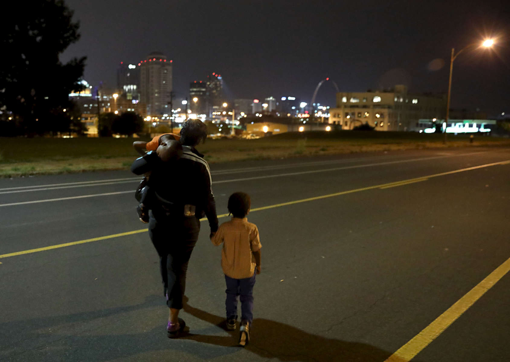 Donna Green and her sons Chris Allen (right), 3, and Donovan Allen, 2, crosses Chouteau Avenue shortly before 5 a.m. in the morning as they head to the bus stop on Monday, Aug. 14, 2017. Green works at a McDonalds in north St. Louis County and needs to leave her home in St. Louis City before 5 a.m. to catch two buses to drop her children at daycare. She then takes another bus to work.Photo by David Carson, dcarson@post-dispatch.com