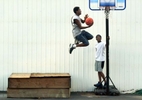 July 22, 2002--Sharron Johnson,15, leaps from the box at the left to get enough elevation to dunk the basketball as his friend Clarence Wigfall, 13, watches him take flight on Tuesday in Maryville.   The boys say they can be found playing basketball most afternoons.Photo BY David Carson/PD