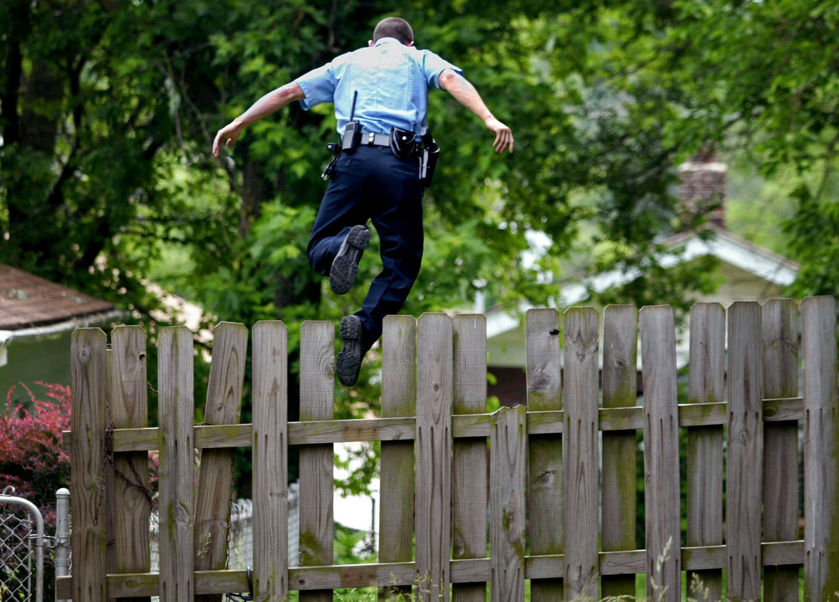 Monday June 2, 2008--Pine Lawn police officer Matthew Meinen leaps off a fence in pursuit of a suspect who fled from police that were patroling a Pine Lawn neighborhood in golf carts.  Meinen was called to scene to in his patrol car to assist when the subjects fled.David Carson | Post-Dispatch