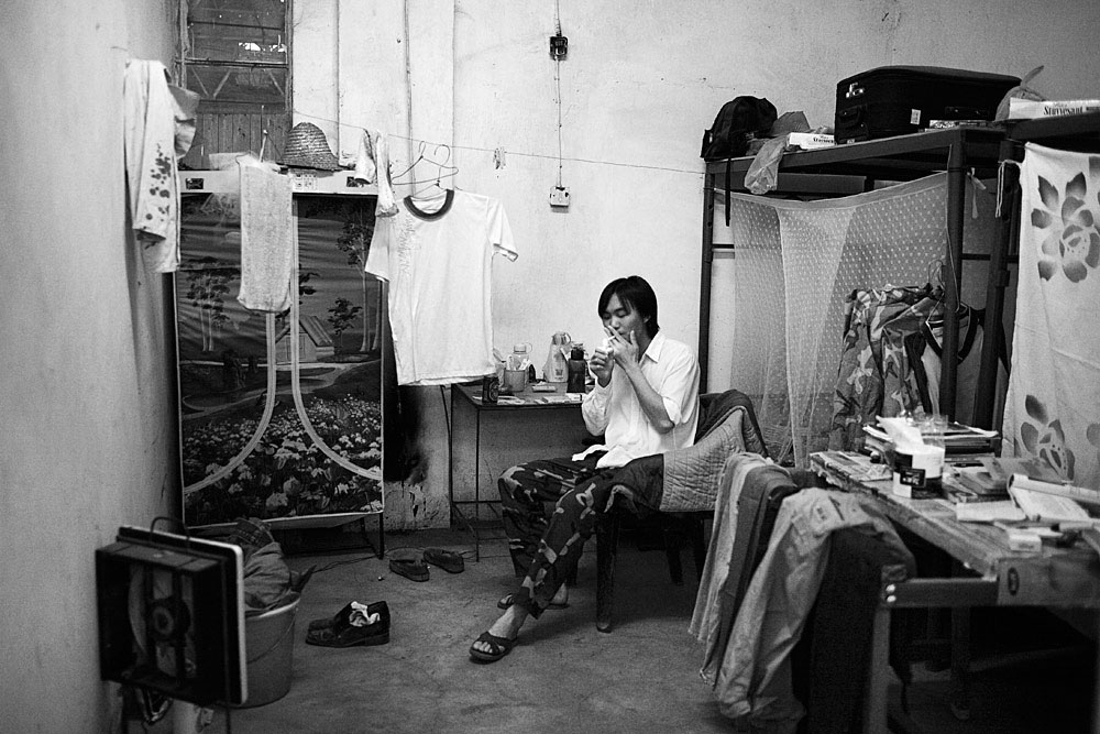 Pan-De, age 26, a Chinese supervisor, lights a cigarette in his small room next to a copper smelter, Ndola, Zambia, 2007. The ore is taken from mines in neighboring Lubumbashi, DRC. The copper is later transported by ship to China, fueling their demand for raw materials. 