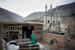 A young girl stands on the roof of the family house in an ancient village, Tuyoq, China, 2007