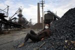 A worker rests on a pile of coal in a steel factory outside Turpan, China, 2007