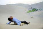 A man rides on a wooden slide in the desert dunes in Gobi desert, DunHuang, China, 2007