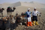 Chinese tourists pose for pictures with camels at the desert dunes in the Gobi desert, DunHuang, China, 2007